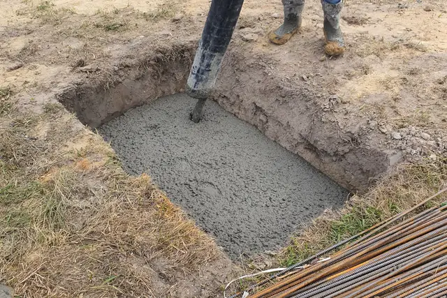 Fresh concrete footing next to a stack of rebar