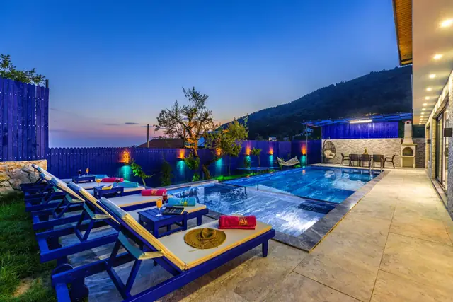 Concrete pool deck with lounge chairs at dusk