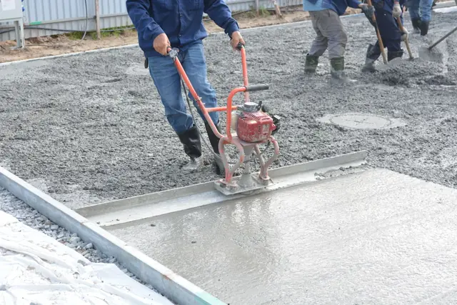 Crew running a power screed across a fresh concrete slab